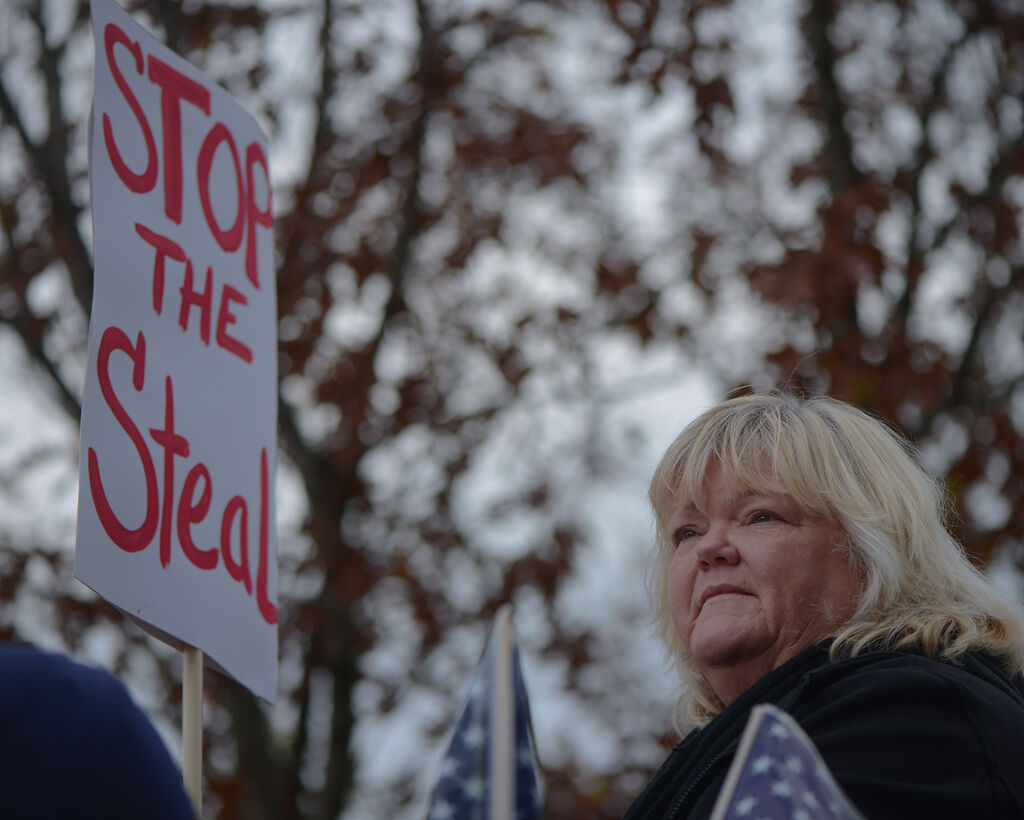 A Trump supporter stands on the balcony of the Missouri State Capitol and looks out onto the people gathered in the street